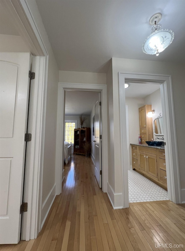hallway featuring light wood finished floors and baseboards
