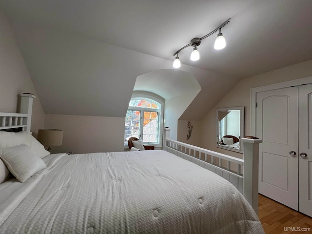 bedroom with a closet, light hardwood / wood-style floors, and lofted ceiling