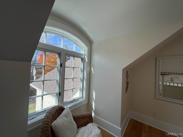sitting room featuring lofted ceiling, baseboards, wood finished floors, and a healthy amount of sunlight