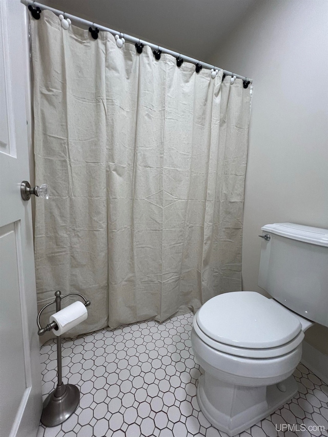 bathroom with toilet, a shower with curtain, and tile patterned floors