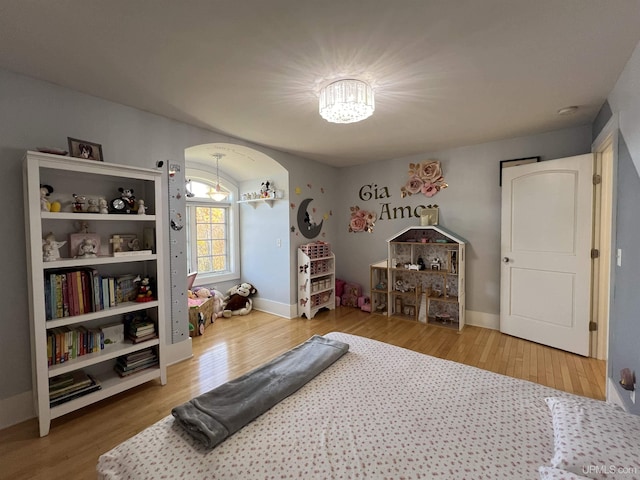 workout room featuring baseboards, wood finished floors, and a notable chandelier