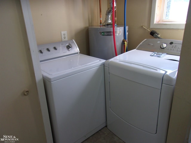 laundry area with water heater, washing machine and clothes dryer, and tile patterned flooring