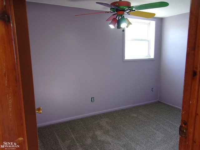 spare room featuring dark colored carpet and ceiling fan