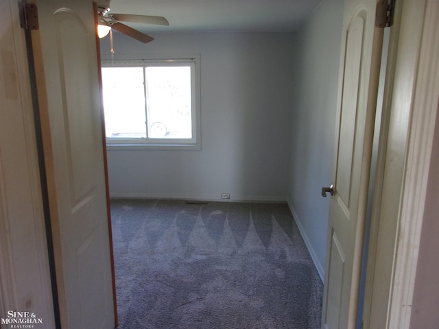 unfurnished room with dark colored carpet and ceiling fan