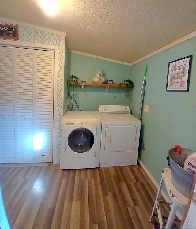 laundry room with ornamental molding, hardwood / wood-style floors, a textured ceiling, and separate washer and dryer