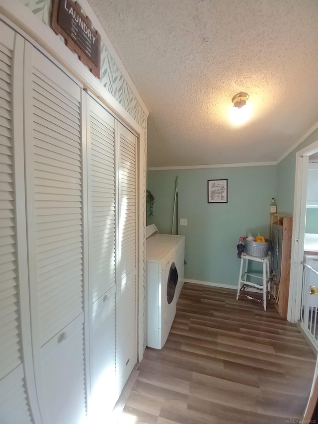 laundry room with ornamental molding, a textured ceiling, washing machine and dryer, and wood-type flooring