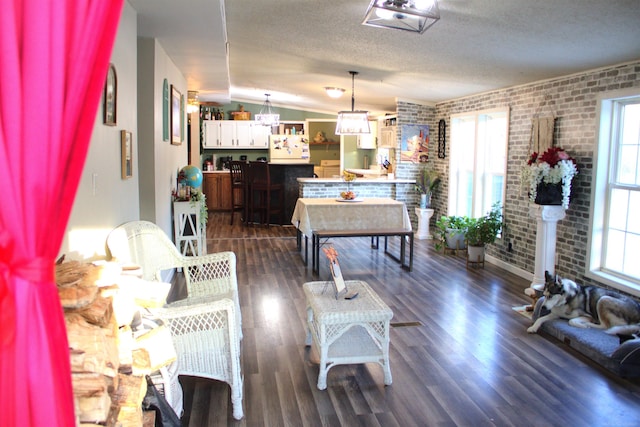 living room featuring brick wall, lofted ceiling, dark hardwood / wood-style flooring, and a textured ceiling