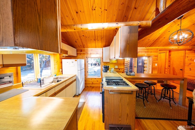 kitchen featuring white cabinetry, white fridge, hanging light fixtures, and a wealth of natural light