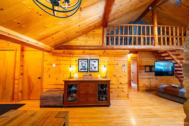 living room with beam ceiling, wooden walls, high vaulted ceiling, and light hardwood / wood-style floors