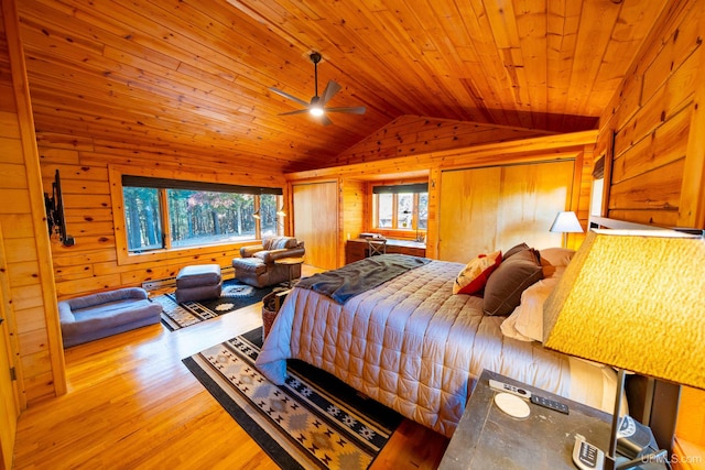 bedroom featuring light hardwood / wood-style flooring, multiple windows, wooden walls, and vaulted ceiling