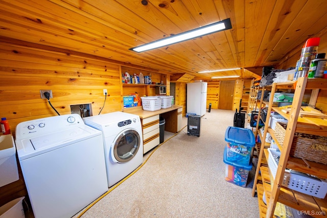 laundry area with light carpet, wood walls, and washing machine and dryer