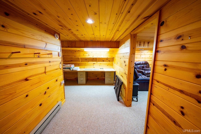 interior space with wood ceiling, wood walls, built in desk, and a baseboard heating unit