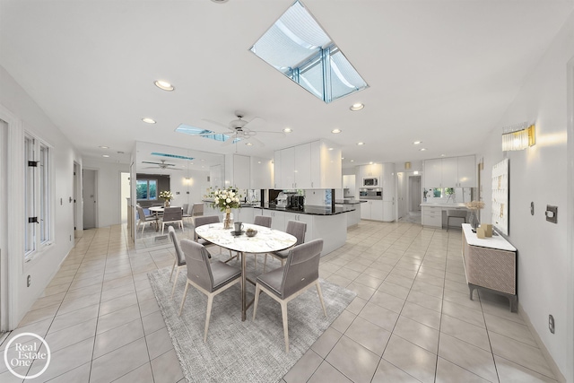 dining space featuring a skylight, ceiling fan, recessed lighting, and light tile patterned floors
