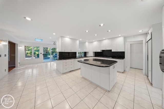 kitchen with backsplash, a center island, dark countertops, and white cabinets