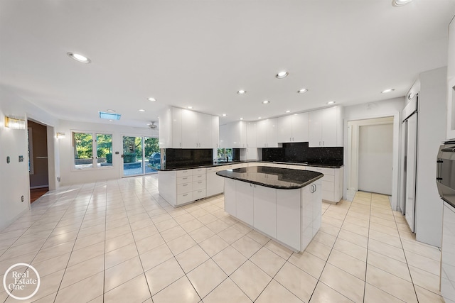 kitchen featuring decorative backsplash, a kitchen island, a barn door, light tile patterned flooring, and white cabinetry