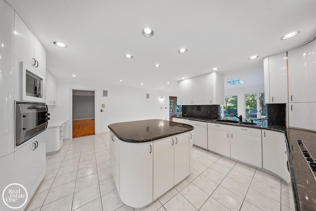 kitchen featuring sink, a kitchen island, stainless steel oven, white cabinetry, and light tile patterned floors