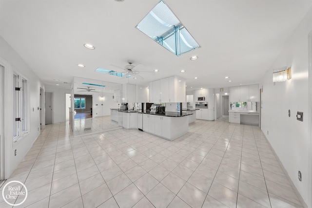 living room featuring a skylight, a ceiling fan, recessed lighting, and light tile patterned floors