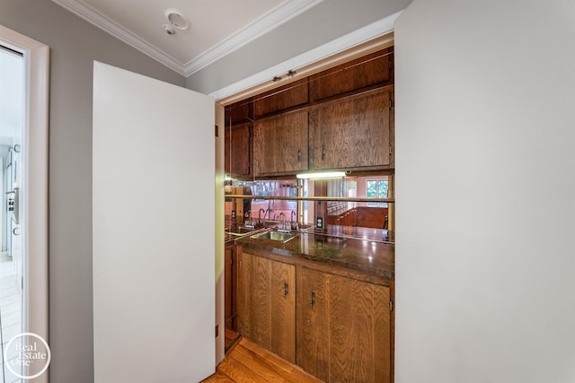 kitchen featuring sink, ornamental molding, and light hardwood / wood-style flooring