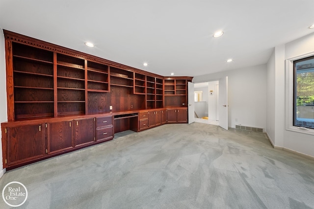 unfurnished office featuring built in desk and light colored carpet