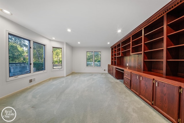 unfurnished living room featuring built in desk and light carpet