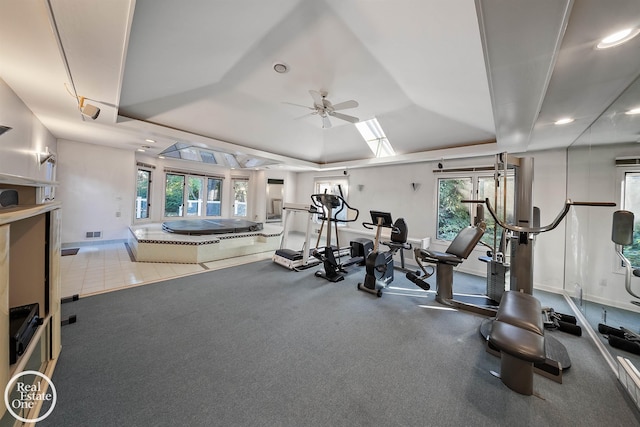 workout area featuring ceiling fan, a skylight, and plenty of natural light