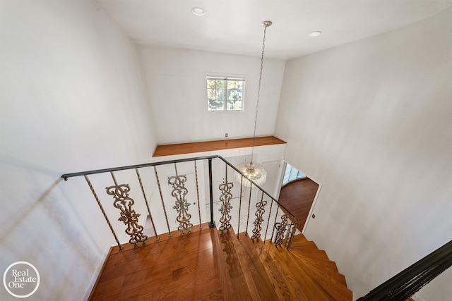 stairs featuring a notable chandelier, wood finished floors, and recessed lighting