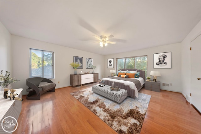 bedroom featuring ceiling fan, hardwood / wood-style flooring, and multiple windows