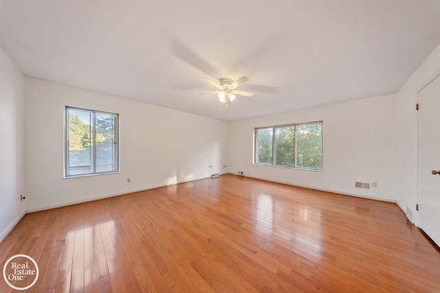 spare room featuring light wood-style floors, visible vents, baseboards, and ceiling fan