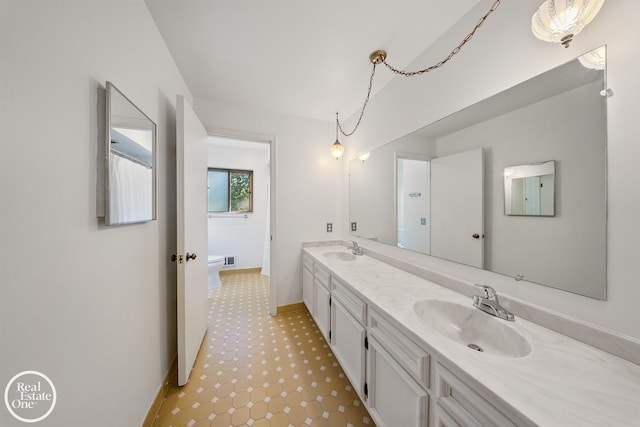 bathroom featuring double vanity, tile patterned floors, toilet, and a sink
