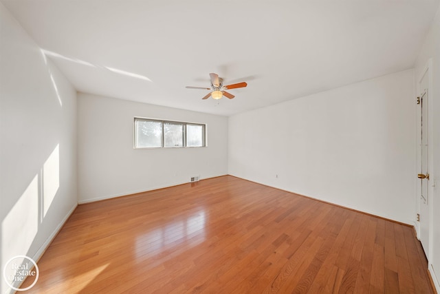 spare room with light wood-type flooring, visible vents, a ceiling fan, and baseboards