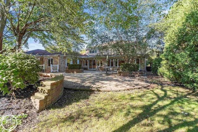 back of property with brick siding, a yard, and a patio