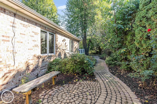 view of property exterior featuring brick siding and a patio
