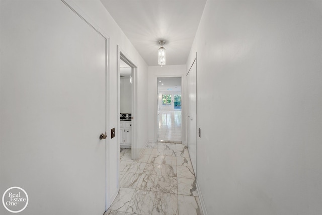 hallway featuring marble finish floor and baseboards