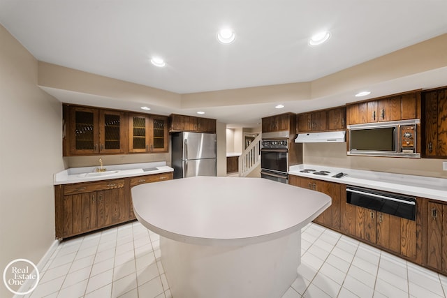 kitchen with light tile patterned floors, a kitchen island, stainless steel refrigerator, black double oven, and sink