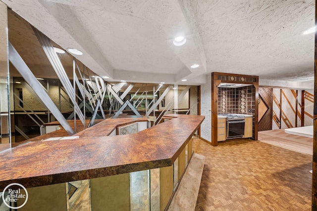 interior space with stainless steel stove, a textured ceiling, and parquet floors