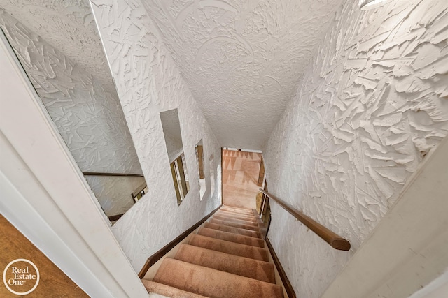 staircase with wallpapered walls and a textured ceiling