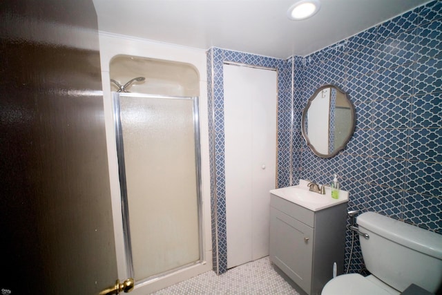 bathroom featuring vanity, a shower with shower door, toilet, and tile walls