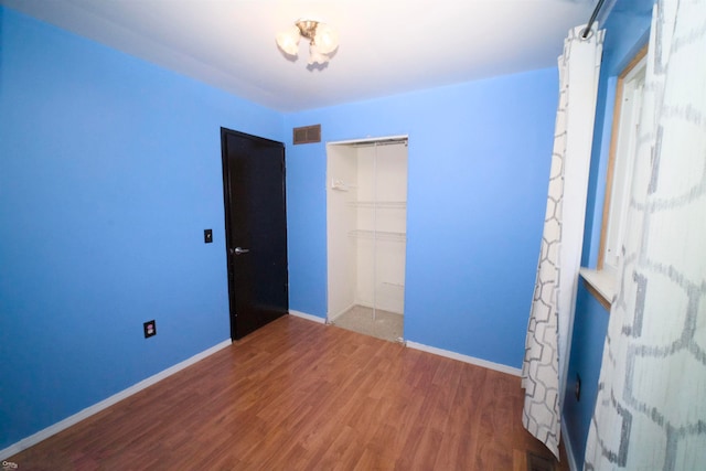 unfurnished bedroom featuring a closet and hardwood / wood-style flooring