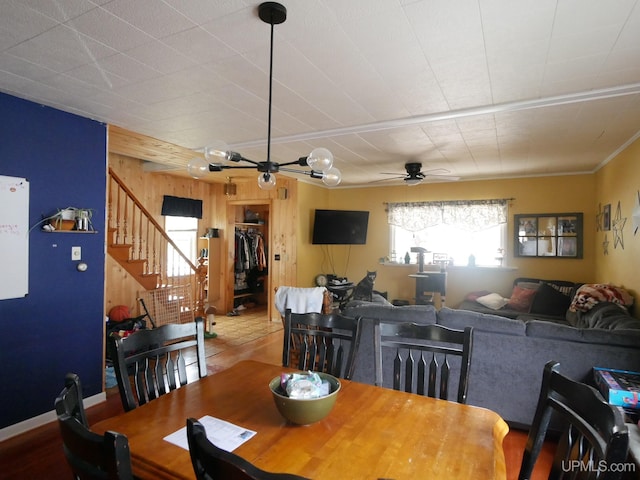 dining room with ceiling fan and wooden walls