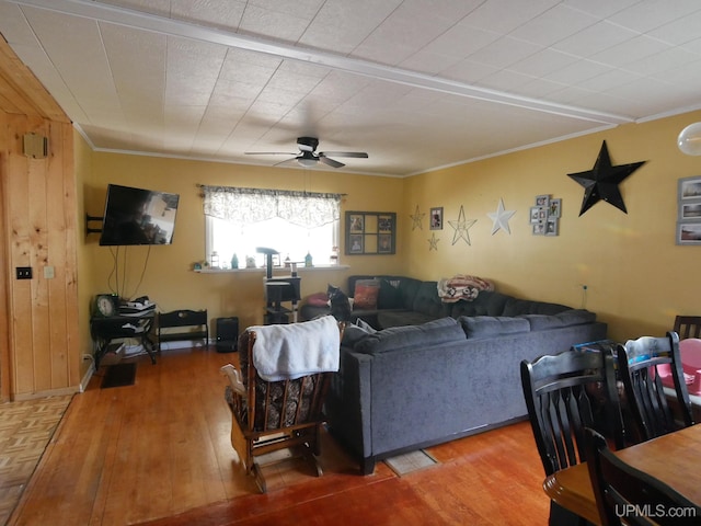 living room featuring wooden walls, crown molding, hardwood / wood-style flooring, and ceiling fan