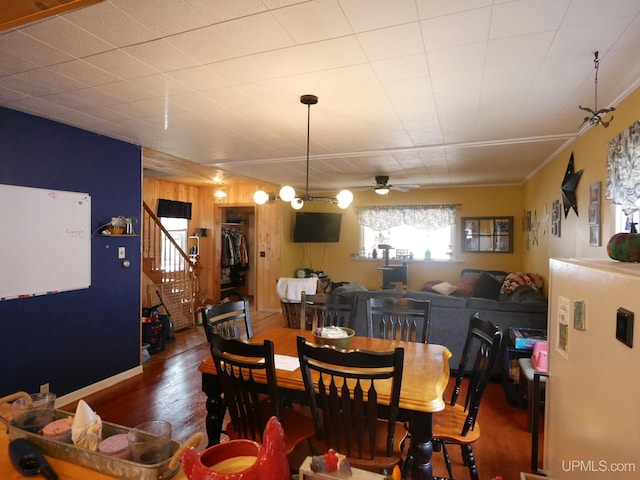 dining space featuring hardwood / wood-style floors, wooden walls, and ceiling fan