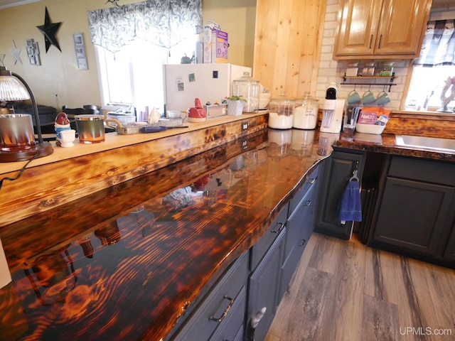 kitchen featuring dark wood-type flooring, decorative backsplash, and dark stone counters