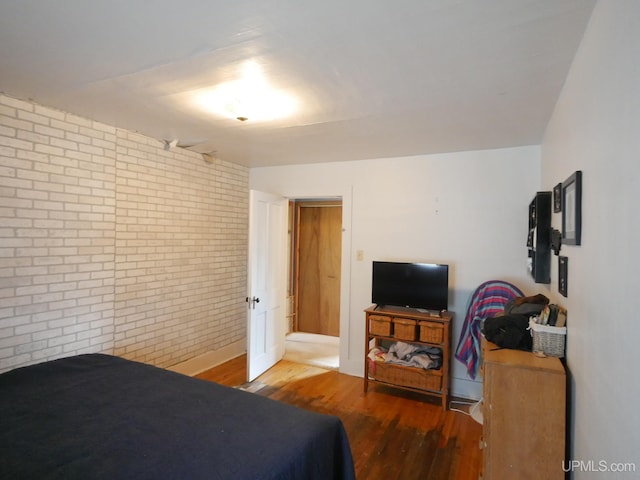 bedroom with brick wall and wood-type flooring