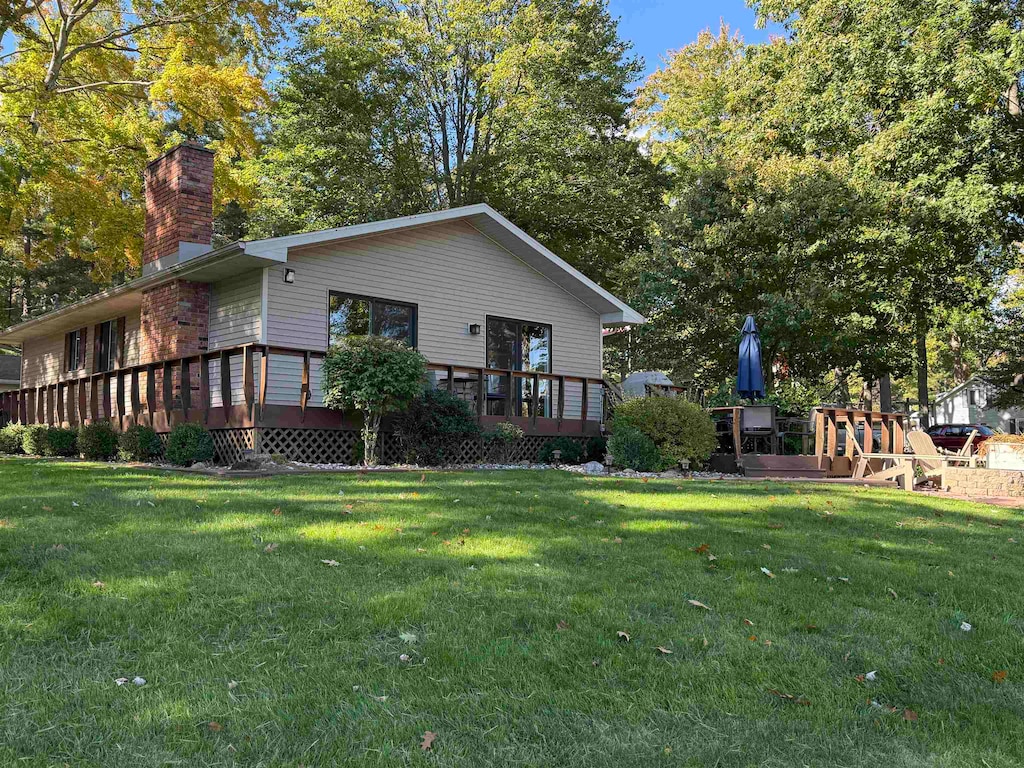 rear view of property featuring a yard and a deck