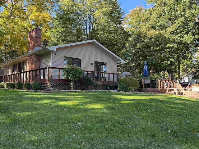 rear view of property featuring a yard and a deck