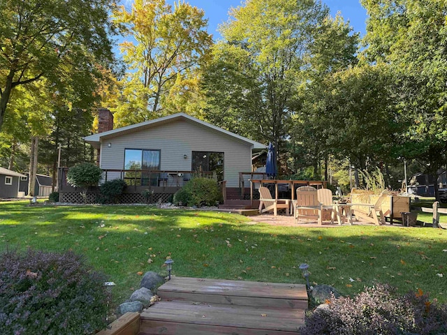 back of house featuring an outdoor fire pit, a lawn, and a wooden deck