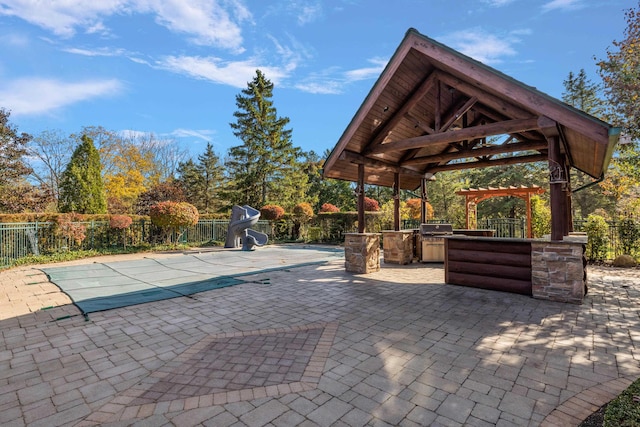 view of swimming pool featuring a patio, a water slide, a gazebo, and an outdoor kitchen