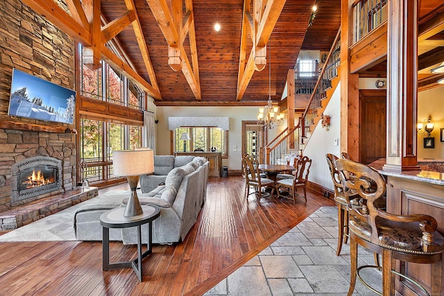 living room featuring beamed ceiling, a fireplace, high vaulted ceiling, and wooden ceiling