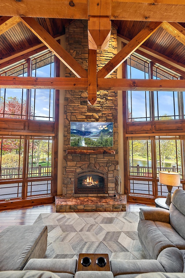 living room with hardwood / wood-style flooring, high vaulted ceiling, a stone fireplace, and beamed ceiling