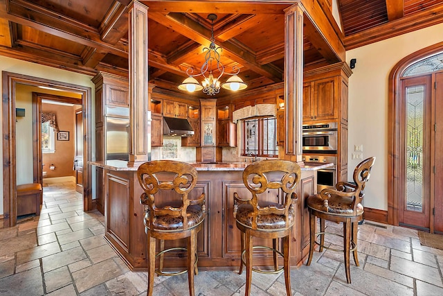 kitchen featuring beam ceiling, coffered ceiling, light stone countertops, and decorative light fixtures